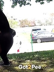 15 pictures - Dark haired woman is filmed pissing by a tree