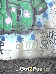 15 pictures - Sexy brunette pisses in the city on drain pipe