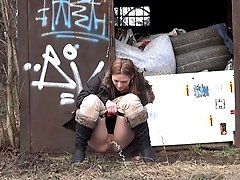 0  - Brunette girl pulls down her trousers to pee outside