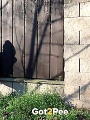 15 pictures - Brunette pees as she leans on a wall