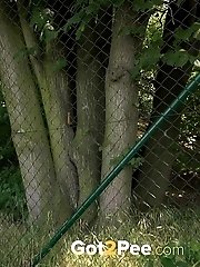 15 pictures - Brunette pissing outside next to a fence