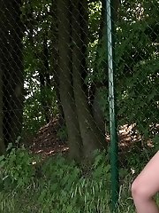 15 pictures - Brunette pissing outside next to a fence